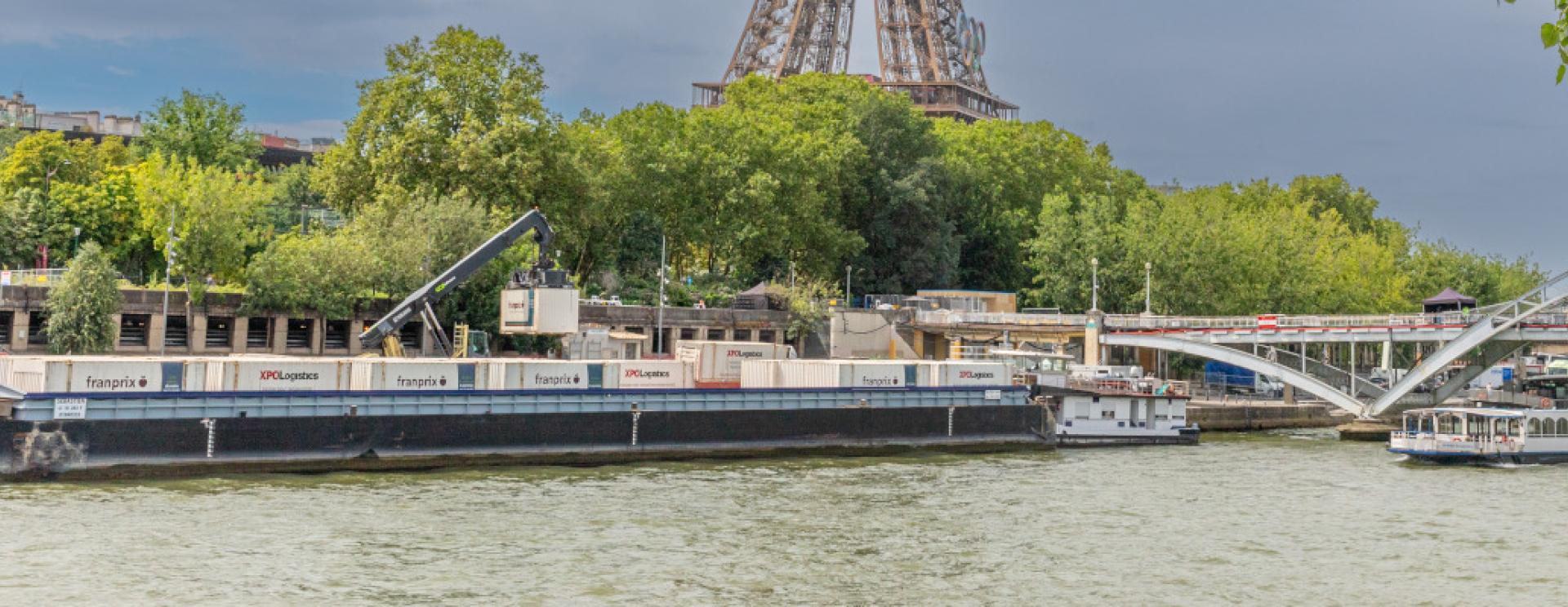 Port de Bourdonnais à Paris, situé au pied la tour Eiffel. Barge en escale et navette fluviale en mouvement. 